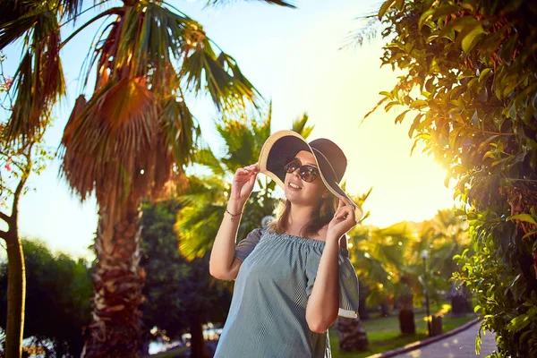 ボドルム、トルコで晴れた日に熱帯ヤシの木の下を歩くビーチ帽子の若い美しい女性。休暇アウトドア海夏旅行の概念 — ストック写真