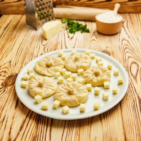 Грузинские пельмени Хинкали с сыром, зеленью и острым томатным соусом Сацебели на белой тарелке — стоковое фото