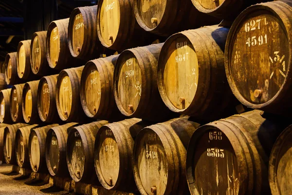 Viejos barriles de madera tradicionales envejecidos con vino en una bóveda alineada en una bodega fresca y oscura en Italia, Oporto, Portugal, Francia — Foto de Stock