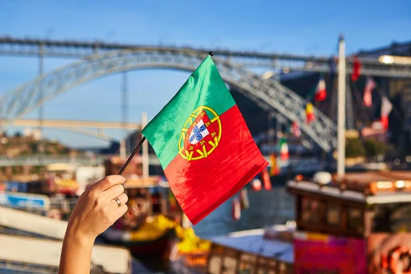 Bandera portuguesa como símbolo de Portugal en el fondo del puente Ponte de Dom Luis I en terraplén cerca del río Doure en Oporto —  Fotos de Stock