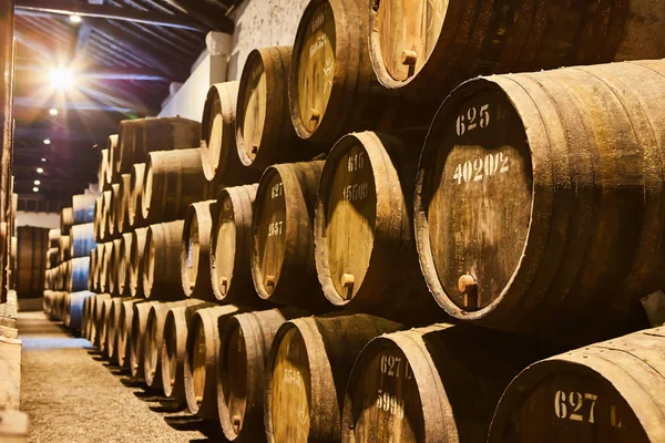 Viejos barriles de madera tradicionales envejecidos con vino en una bóveda alineada en una bodega fresca y oscura en Italia, Oporto, Portugal, Francia — Foto de Stock