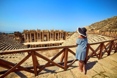 Antik Hierapolis, Pamukkale, Türkiye'deki muhteşem Amfitiyatro kalıntılarına şapkalı kadın gezginin arka görünümü. Büyük panorama