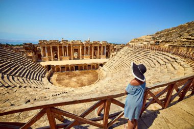 Antik Hierapolis, Pamukkale, Türkiye'deki muhteşem Amfitiyatro kalıntılarına şapkalı kadın gezginin arka görünümü. Büyük panorama