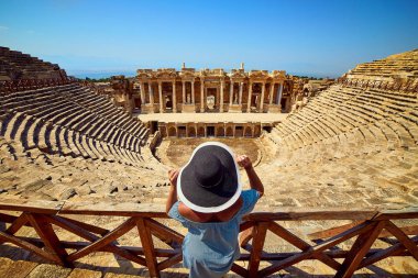 Antik Hierapolis, Pamukkale, Türkiye'deki muhteşem Amfitiyatro kalıntılarına şapkalı kadın gezginin arka görünümü. Büyük panorama