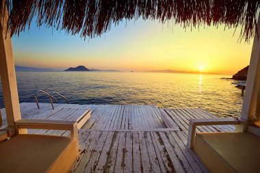 Gün batımında denizde bungalov. Kumlu bir plajın kıyısında ahşap köşkler - Bodrum, Türkiye 