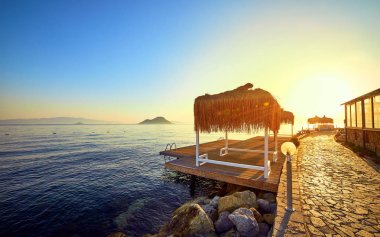 Gün batımında denizde bungalov. Kumlu bir plajın kıyısında ahşap köşkler - Bodrum, Türkiye 