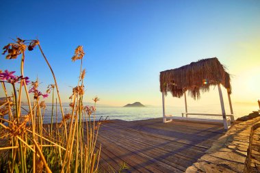 Gün batımında denizde bungalov. Kumlu bir plajın kıyısında ahşap köşkler - Bodrum, Türkiye 