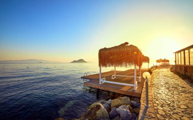 Gün batımında denizde bungalov. Kumlu bir plajın kıyısında ahşap köşkler - Bodrum, Türkiye 