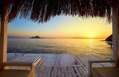 Gün batımında denizde bungalov. Kumlu bir plajın kıyısında ahşap köşkler - Bodrum, Türkiye 