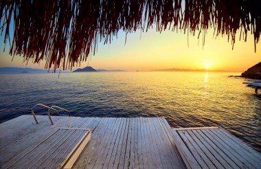 Gün batımında denizde bungalov. Kumlu bir plajın kıyısında ahşap köşkler - Bodrum, Türkiye 