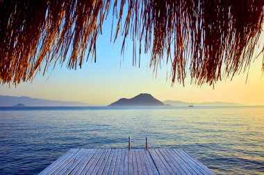 Gün batımında denizde bungalov. Kumlu bir plajın kıyısında ahşap köşkler - Bodrum, Türkiye 