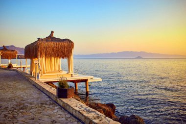 Gün batımında denizde bungalov. Kumlu bir plajın kıyısında ahşap köşkler - Bodrum, Türkiye 