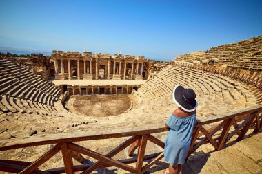 Antik Hierapolis, Pamukkale, Türkiye'deki muhteşem Amfitiyatro kalıntılarına şapkalı kadın gezginin arka görünümü. Büyük panorama
