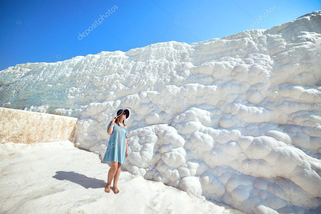 Young girl in hat looking on travertine pools and terraces in Pamukkale. Cotton castle in southwestern Turkey