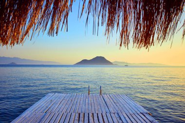 Gün batımında denizde bungalov. Kumlu bir plajın kıyısında ahşap köşkler - Bodrum, Türkiye 