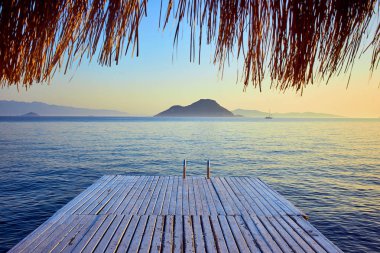 Gün batımında denizde bungalov. Kumlu bir plajın kıyısında ahşap köşkler - Bodrum, Türkiye 