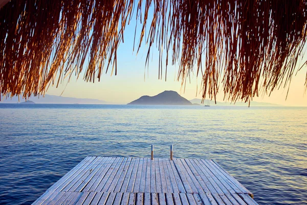 Gün batımında denizde bungalov. Kumlu bir plajın kıyısında ahşap köşkler - Bodrum, Türkiye 