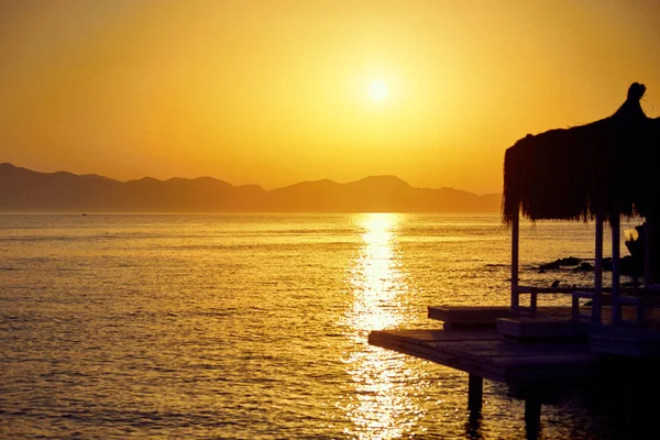 Bungalow am Meer bei Sonnenuntergang. Holzpavillons am Ufer eines Sandstrandes - Bodrum, Truthahn — Stockfoto