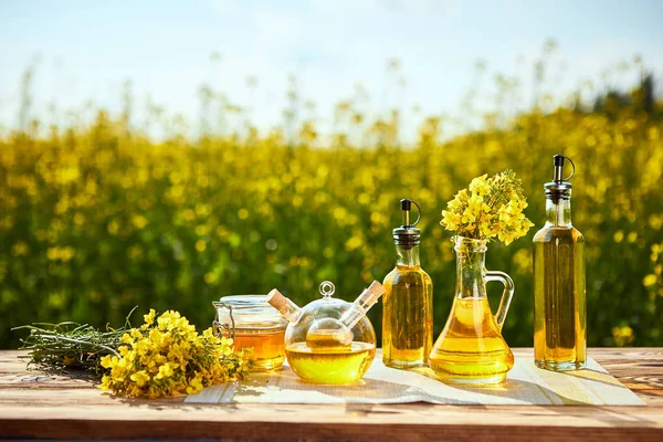 Rapeseed oil bottles (canola) on background rape field