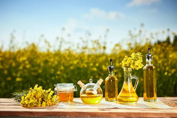 Rapeseed oil bottles (canola) on background rape field