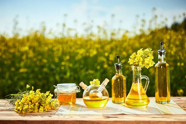 Rapeseed oil bottles (canola) on background rape field