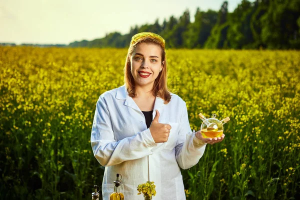 若い美しい生物学者や農学者は、菜種油の品質を調べます。アグリビジネスのコンセプト — ストック写真