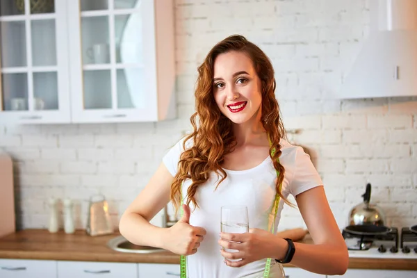 Fiatal nő iszik édesvíz üvegből, és bemutatja remek a konyhában. Egészséges életmód és étkezés. Egészség, szépség, diéta koncepció. — Stock Fotó
