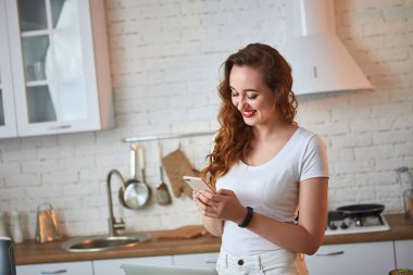 Modern mutfakta yemek yaparken onun akıllı telefon kullanarak genç güzel kadın. Sağlıklı gıda ve Diyet kavramı. Kilo Verme