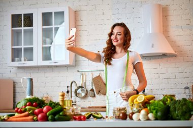 Genç güzel kadın modern mutfakta yemek yaparken selfie çekmek. Sağlıklı gıda ve Diyet kavramı. Kilo Verme