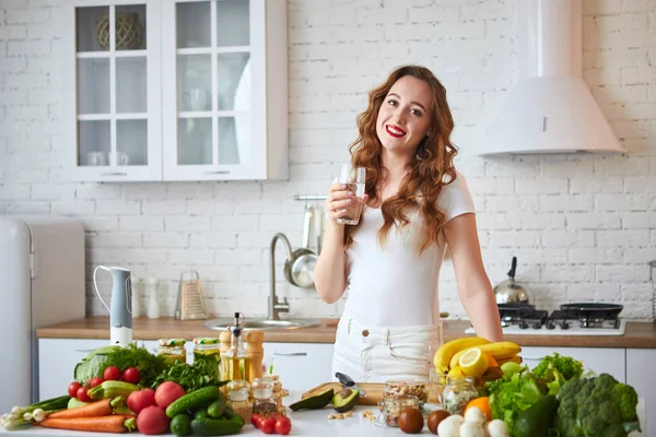 Fiatal nő iszik friss vizet üvegből a konyhában. Egészséges életmód és étkezés. Egészség, szépség, diéta koncepció. — Stock Fotó