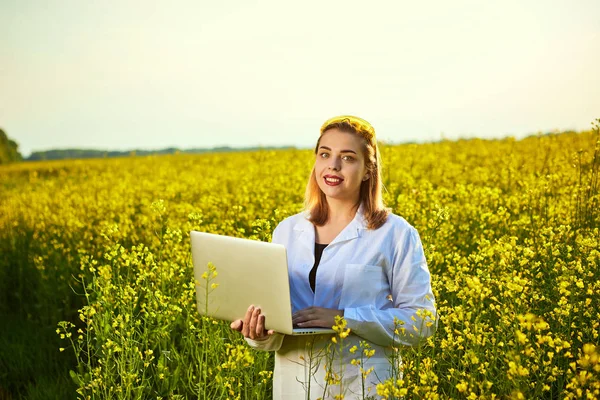 Agronomist kadın veya çiftçi defter kullanarak çiçek tecavüz (kanola) alanı incelemek — Stok fotoğraf