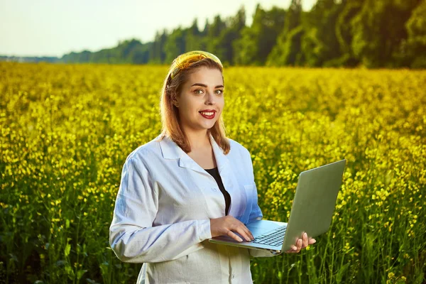 Agronomist kadın veya çiftçi defter kullanarak çiçek tecavüz (kanola) alanı incelemek — Stok fotoğraf