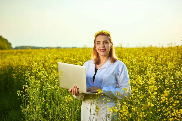 Agronomist kadın veya çiftçi defter kullanarak çiçek tecavüz (kanola) alanı incelemek — Stok fotoğraf