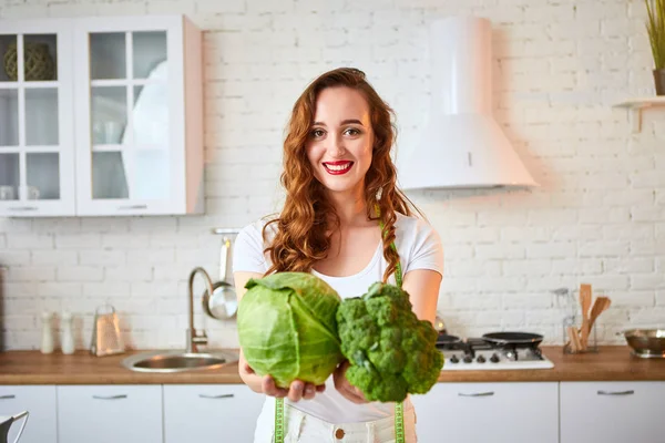 Fiatal boldog nő gazdaság brokkoli és káposzta a gyönyörű konyhában, zöld friss alapanyagokból beltérben. Egészséges táplálkozás és a fogyókúra fogalmát. Elvesztése súly — Stock Fotó