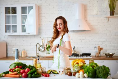 Salatalık, limon ve yapraklı genç kadın ile tatlı su içen genç kadın mutfakta camdan salatalık, limon ve nane yaprakları ile tatlı su içiyor. Sağlıklı Yaşam Tarzı ve Yeme. Sağlık, Güzellik, Diyet Kavramı.