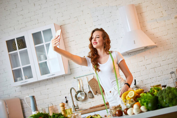 Young beautiful woman take a selfie while cooking in the modern kitchen. Healthy food and Dieting concept. Losing Weight