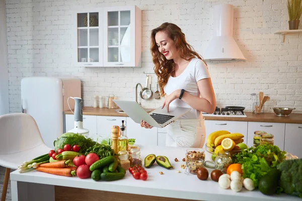 Mladá krásná žena, která při vaření v moderní kuchyni používá zápisník. Zdravá strava a dieting koncepce. Ztráta hmotnosti — Stock fotografie