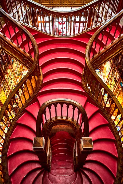 Gran escalera de madera con escalones rojos dentro de la librería Livraria Lello en el centro histórico de Oporto, famosa por la película de Harry Potter . — Foto de Stock