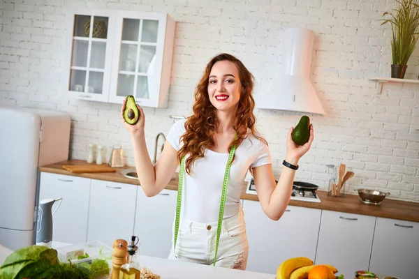 Fiatal boldog nőt gazdaság avokádó készítésére saláta a gyönyörű konyhában, zöld friss alapanyagokból beltéri. Egészséges táplálkozás és a fogyókúra fogalmát. Elvesztése súly — Stock Fotó