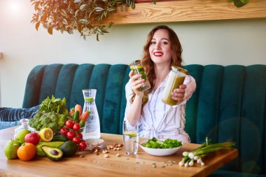Genç kadın arka plan ve taze meyve ve sebzeler üzerinde yeşil çiçekler ile güzel iç Smoothie ve taze su içme. Sağlıklı yeme konsepti. Vegan yemek ve Detox menüsü