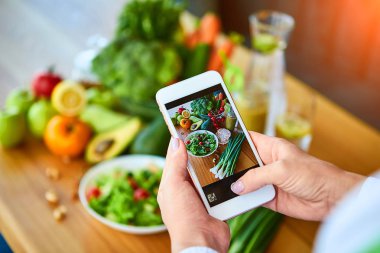 Kadın eller domates ve meyveler ile sebze salatası Smartphone gıda fotoğraf çekmek. Sosyal medya veya bloglama için telefon fotoğrafçılığı. Vegan Öğle Yemeği, Vejetaryen akşam yemeği, sağlıklı diyet 
