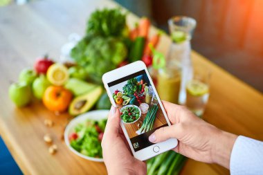 Kadın eller domates ve meyveler ile sebze salatası Smartphone gıda fotoğraf çekmek. Sosyal medya veya bloglama için telefon fotoğrafçılığı. Vegan Öğle Yemeği, Vejetaryen akşam yemeği, sağlıklı diyet 