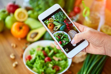 Kadın eller domates ve meyveler ile sebze salatası Smartphone gıda fotoğraf çekmek. Sosyal medya veya bloglama için telefon fotoğrafçılığı. Vegan Öğle Yemeği, Vejetaryen akşam yemeği, sağlıklı diyet 