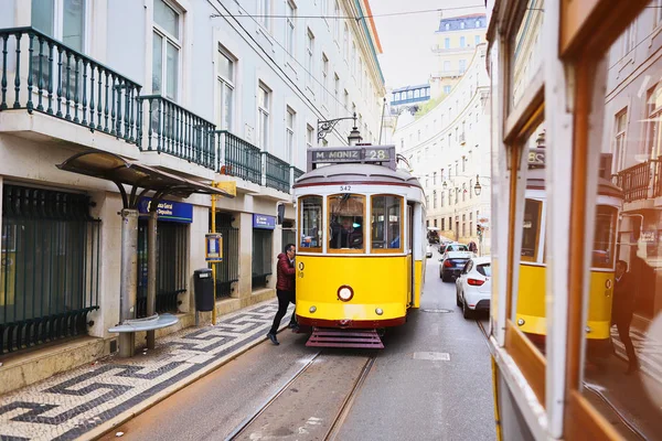 LISBONA, PORTOGALLO, 12 dicembre 2018: tram storico in legno giallo vintage 28 che attraversa Lisbona, simbolo della città. Trasporto indispensabile per la gente del posto e attrazione interessante per i turisti — Foto Stock