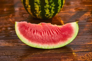 Bulanık bahçe günbatımı arka plan ile ahşap masa üzerinde Taze olgun çizgili dilimlenmiş karpuz. Gıda, Meyve veya sağlık konsepti.