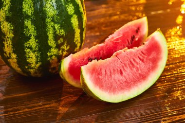 Bulanık bahçe günbatımı arka plan ile ahşap masa üzerinde Taze olgun çizgili dilimlenmiş karpuz. Gıda, Meyve veya sağlık konsepti.