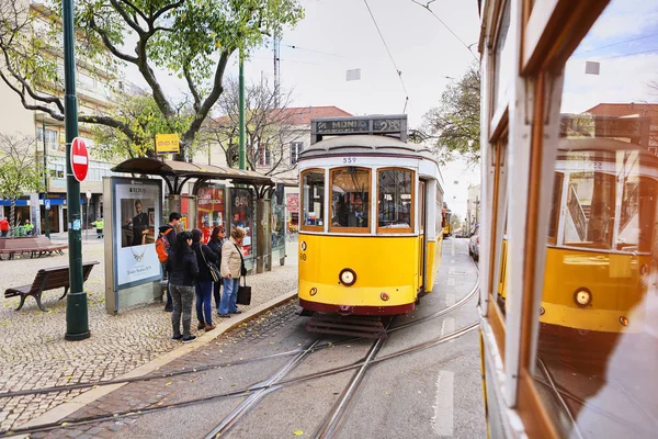 LISBONA, PORTOGALLO, 12 dicembre 2018: tram storico in legno giallo vintage 28 che attraversa Lisbona, simbolo della città. Trasporto indispensabile per la gente del posto e attrazione interessante per i turisti — Foto Stock