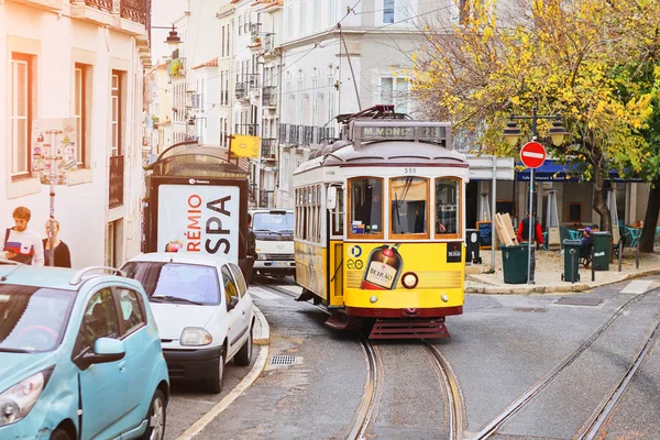 LISBONA, PORTOGALLO, 12 dicembre 2018: tram storico in legno giallo vintage 28 che attraversa Lisbona, simbolo della città. Trasporto indispensabile per la gente del posto e attrazione interessante per i turisti — Foto Stock