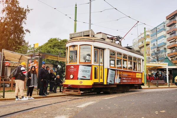 LISBONA, PORTOGALLO, 12 dicembre 2018: tram storico in legno giallo vintage 28 che attraversa Lisbona, simbolo della città. Trasporto indispensabile per la gente del posto e attrazione interessante per i turisti — Foto Stock