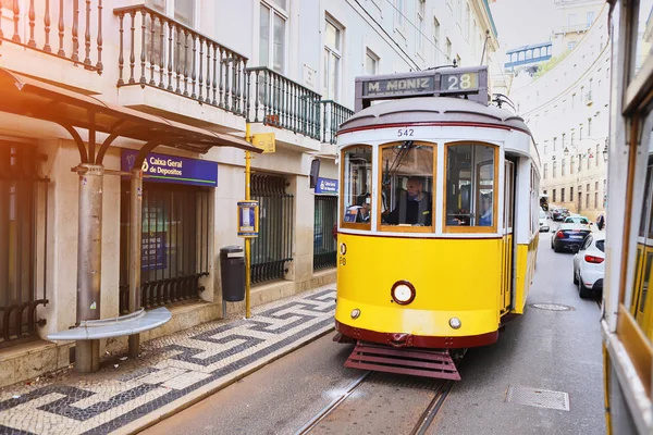 LISBONA, PORTOGALLO, 12 dicembre 2018: tram storico in legno giallo vintage 28 che attraversa Lisbona, simbolo della città. Trasporto indispensabile per la gente del posto e attrazione interessante per i turisti — Foto Stock